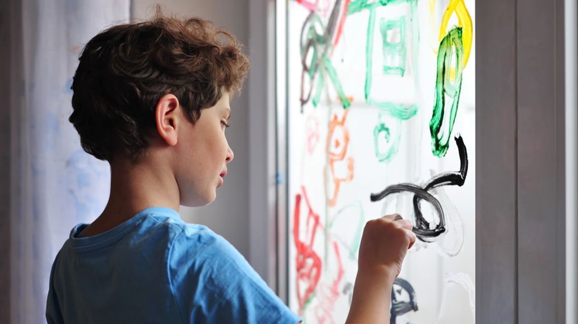 Bambino che disegna su una finestra
